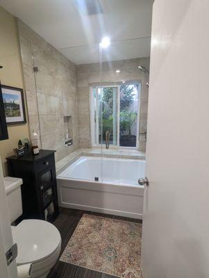 Master bathroom tub/shower combo with new frameless doors and brushed nickel hardware.