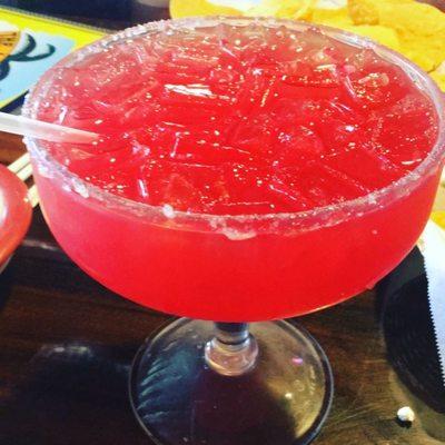 Large strawberry margarita on the rocks with sugar rim