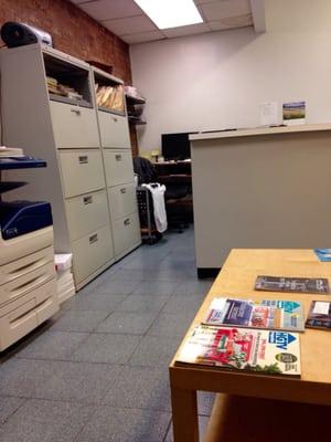 Front desk and table in waiting area. The office is in an old brick building.