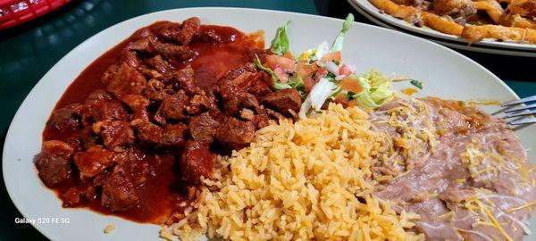 Chile colorado with tasty rice and refried beans.