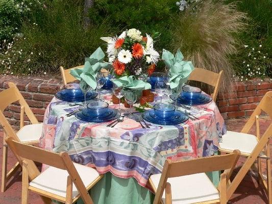 48" round table (seats 6-8) with natural wood chairs. Casblanca cloth overlay on top of Celedon tablecloth.