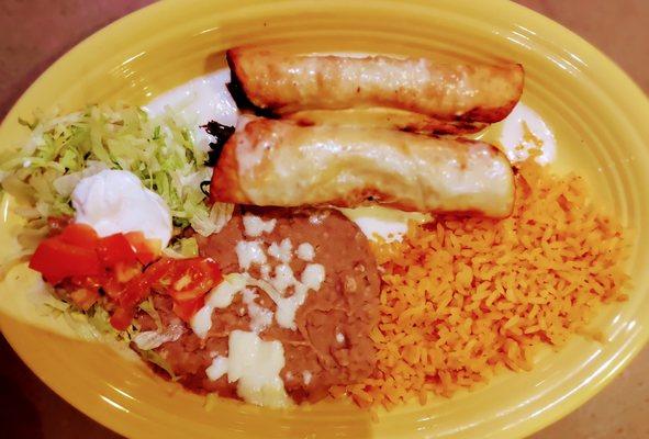 Chimichangas - one beef, one chicken topped with cheese dip.  Served with rice, beans, sour cream and guacamole salad.