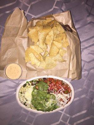 Salad bowl with chicken, black beans, fresh tomato salsa, roasted chili-corn salsa, cheese and guacamole with a side of chips and queso