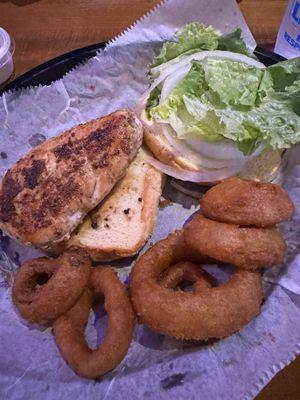 Grilled chicken with onion and lettuce with side of onion rings.