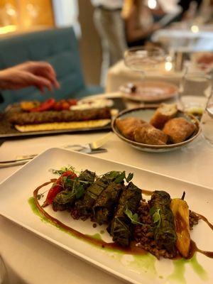 Foreground: Char Grilled Quail Wrapped in Wine Leaves Background: Nar Kebab