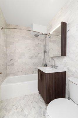 Beautiful Renovated Bathrooms with Glass Tile, Marble Flooring, Rainfall Shower head, and Lighted Medicine Cabinet.