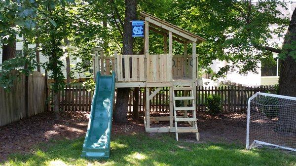 Shed roof on this small playset with a porch, ladder and wave slide.