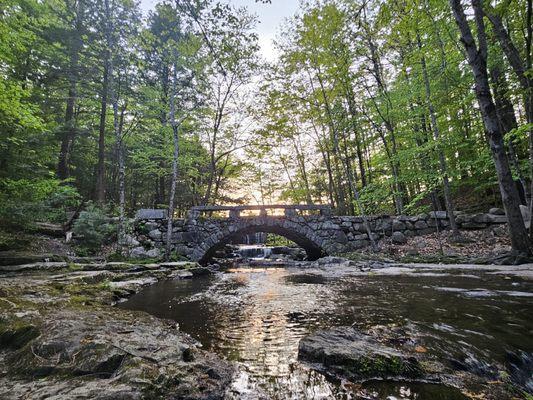 Trail over a bridge leading to small waterfall