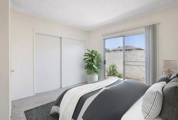 Staged and carpeted bedroom with sliding doors leading to patio.