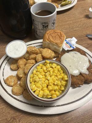 Country fried steak with potato rounds and corn.