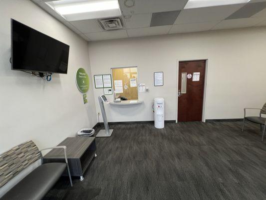 Entrance with seating to left and right, kiosk to check in at far left, and doorway where lab rooms are located is straight ahead