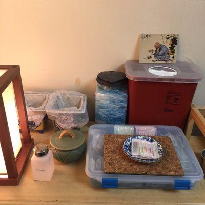 An acupuncture table top with Sharps container, alcohol, cotton balls and sterile one time use thin needles