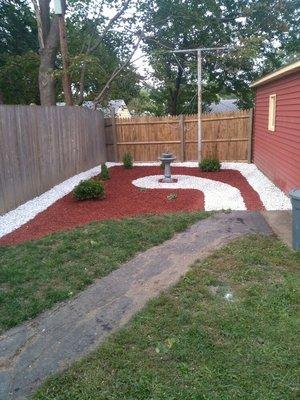 Back yard designed for client using red mulch and white marble stone. Shrubs planted last.