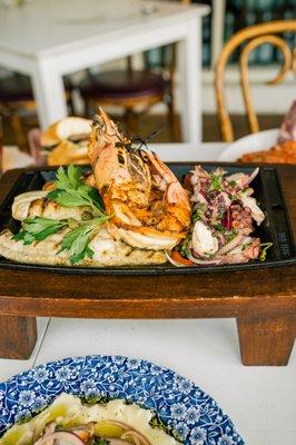 Seafood Parrillada featuring octopus, jumbo tiger prawn, salmon, and branzino.