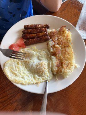 Eggs, hash browns and sausage. With two tiny cubes of watermelon.