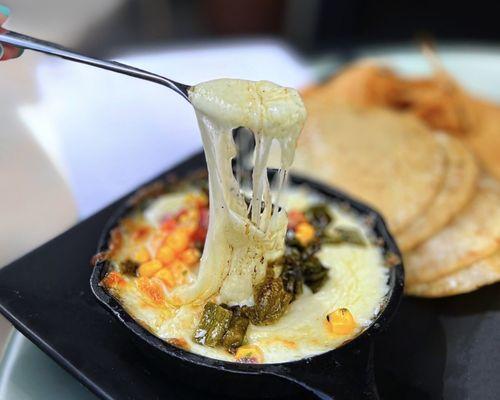 Queso Fundido w/ monterey jack cheese, cilantro, peppers, corn chips or chicharrónes | $9