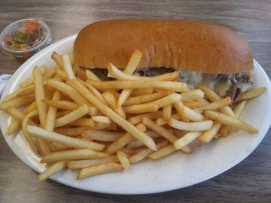 Italian Beef sandwich with cheese and hot peppers and french fries.