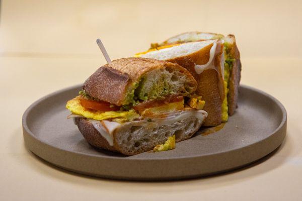 Breakfast Sando- Pesto, Fluffy Eggs, Cheese, Turkey, Veggies, Pickled Jalapeños, Chili Oil.