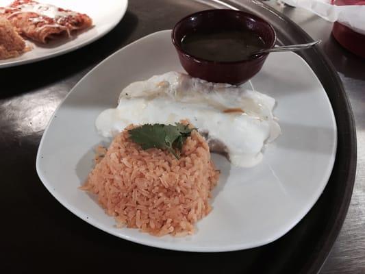 Chicken Enchiladas topped with sour cream, served with rice and charro beans