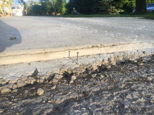 large step-off from driveway to road and SCREWS left stuck into concrete