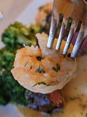 A fork with one of the shrimps of the main entrée.