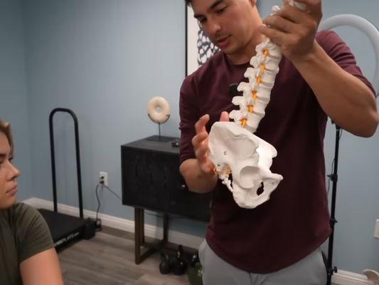 Dr Tyler Bigenho teaching client chiropractic adjustment to alleviate pain