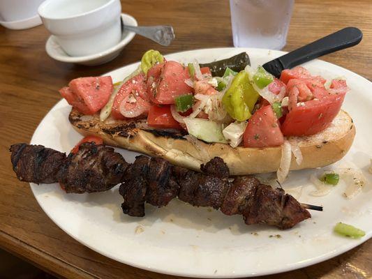 Village salad with pork souvlaki, unclear why the salad is on a large piece of bread