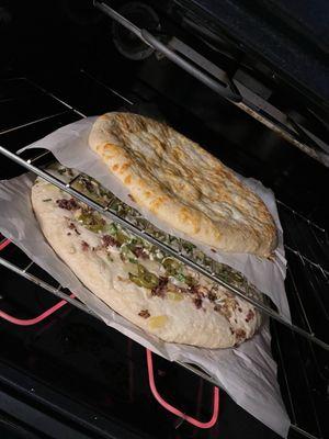 In the oven!  Top: Cheesy garlic bread sticks (medium, 12") Bottom: Boss lady combo pizza (giant, 16")