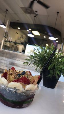 Small bowl with acai, activated charcoal, matcha and chia pudding. With granola, banana, strawberries, blueberries and almond butter.