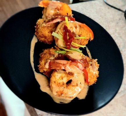 Grilled shrimp over fried grits with a cajun cream sauce.