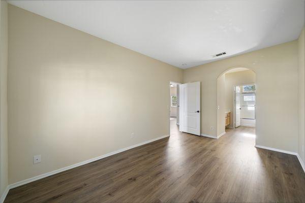 Open floorplan living space with wood plank style flooring and Tuscan style half moon archway