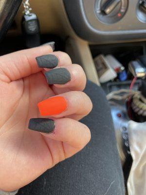 Matte black with spider webs, single plain neon orange nail, they're straight and non chunky