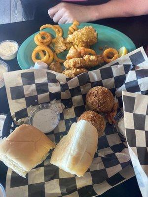 Half finished boudin ball appetizer and fried fish / oyster basket with curly fries.