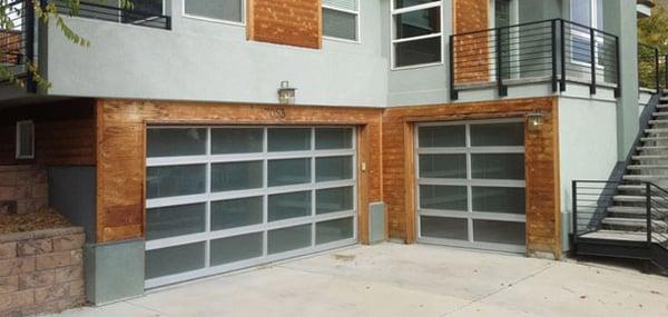 Residential full view modern garage door with glass panels and aluminum frames.