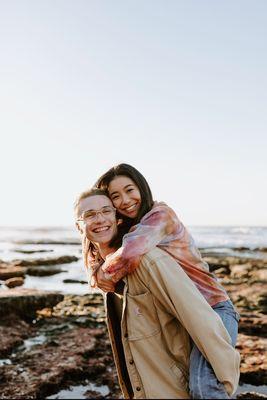 Cute couple doing piggy back on beach in San Diego