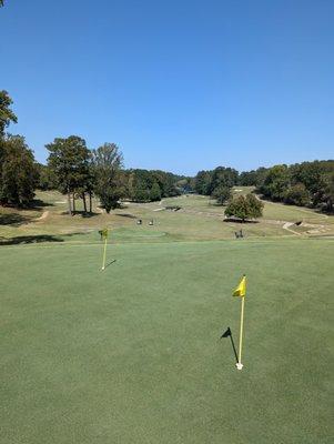 Practice putting green with golf course in background.