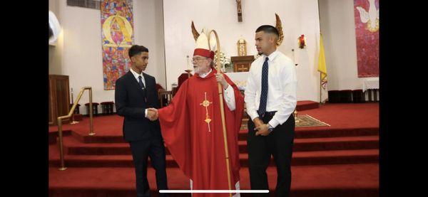 Bishop Gorge Sheltz, auxiliary of Galveston-Houston, congratulating two boys of St Charles Church who were confirmed.