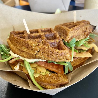 Hummus & Avo BLT Wafflewich: sweet potato waffle, hummus, avo, coconut bacon, smokey mayo, microgreens & tomato + swt potato chips & pickle.