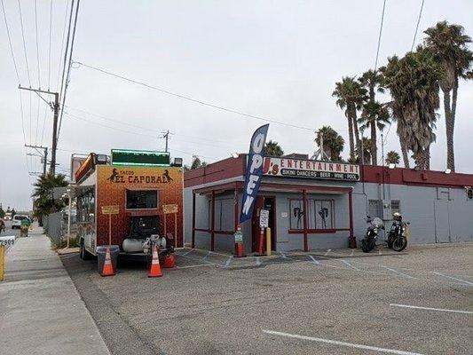 The El Caporal truck is parked in front of a club