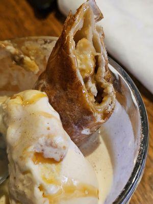 The Flash-Fried Banana Cheesecake in a glass bowl with vanilla ice cream and drizzled with caramel sauce.