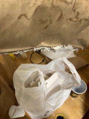 Paper bag on top of an open rice container from carry-out.