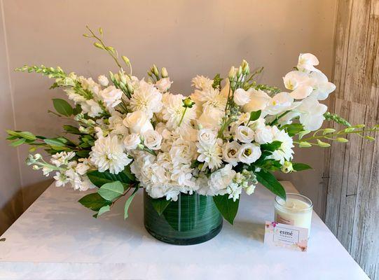 All white dahlias, orchids, roses and lisianthus beautifully arranged in a wraparound glass vase