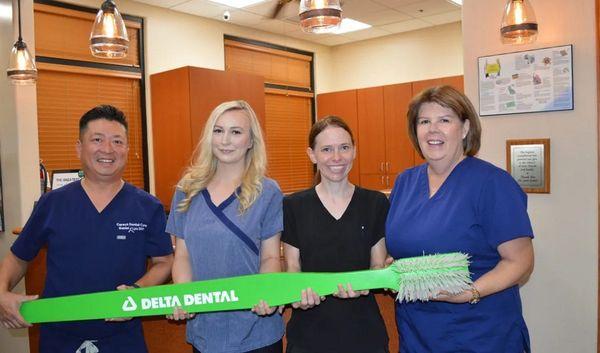 Tempe dentist Dr Daniel Lyu at Cereus Dental Care and his team holding Delta Dental toothbrush