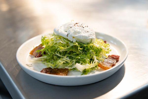 Lyonnaise salad with poached egg, house made bacon, champagne vinaigrette