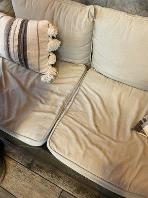 Stained, dirty cushions on the lobby bench.