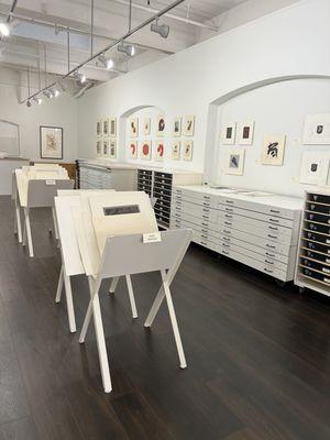 View of gallery interior from the front section of the space, showing wall displays and display bins