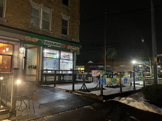 Outside view of this corner shop. There are tables & seats indoor & outdoors. The street parking is limited