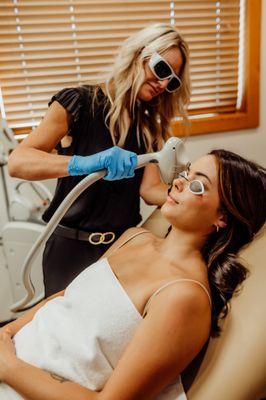 Certified Advanced Aesthetician, Angie Herriges performing IPL treatment on her patient.