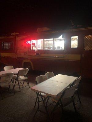 Outdoor seating and the taco truck's order window.