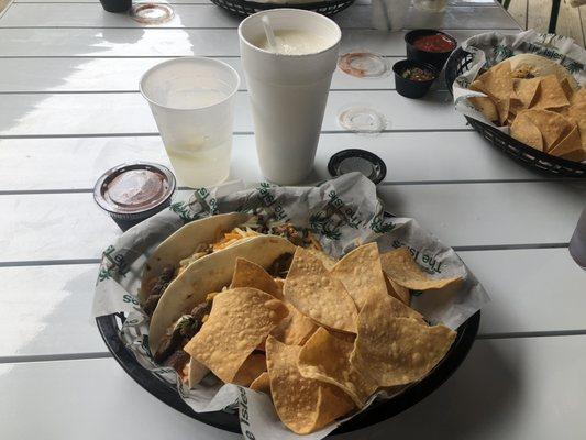 Steak tacos with chips on the side and a frozen margarita.